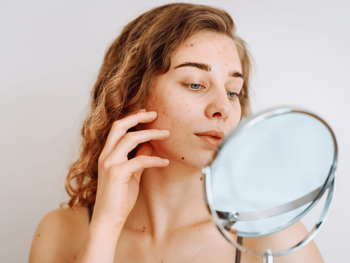 woman looking at face in small mirror